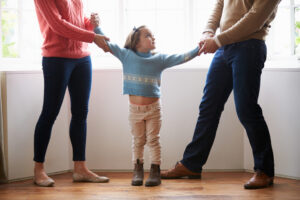 Article 8 A family court judge reviewing child custody documents in Thailand, with a father and mother seated across a wooden desk, symbolizing the custody determination process in Thai family law.